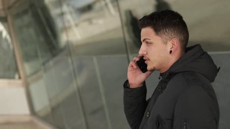 Serious-stylish-guy-with-ear-tunnels-talking-on-phone